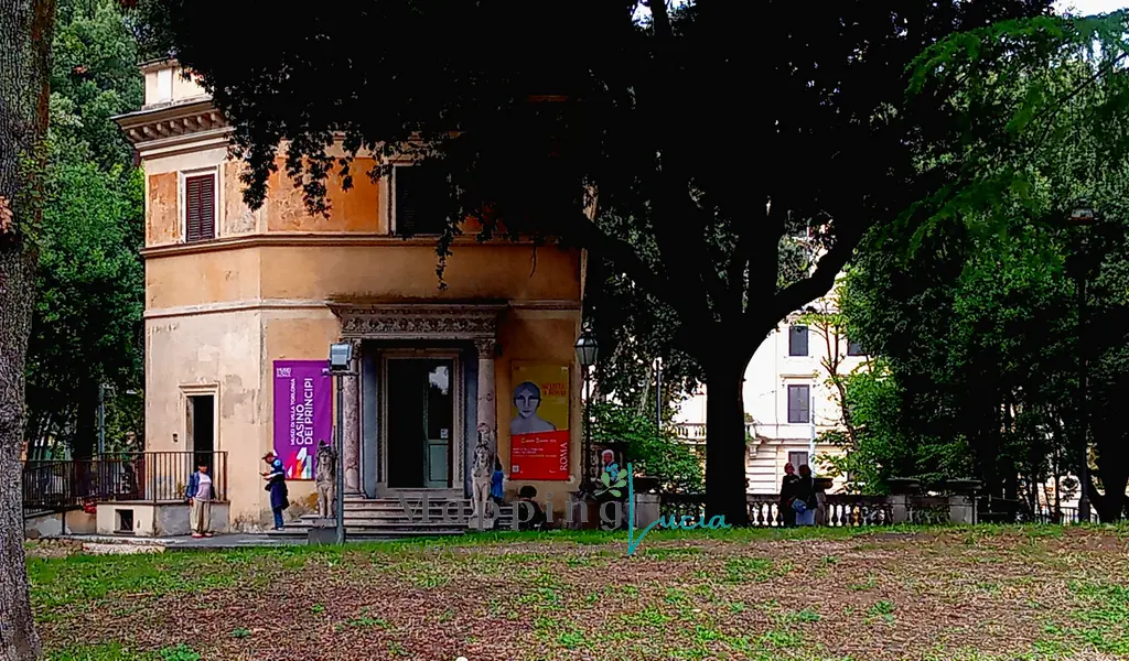 casina-dei-principi-torlonia-immersa-tra-gli-alberi-all-ingresso-il-manifesto-della-mostra-artiste-a-roma